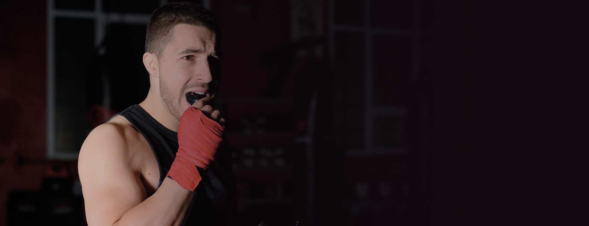 A boxer places his mouth guard wearing read hand padding