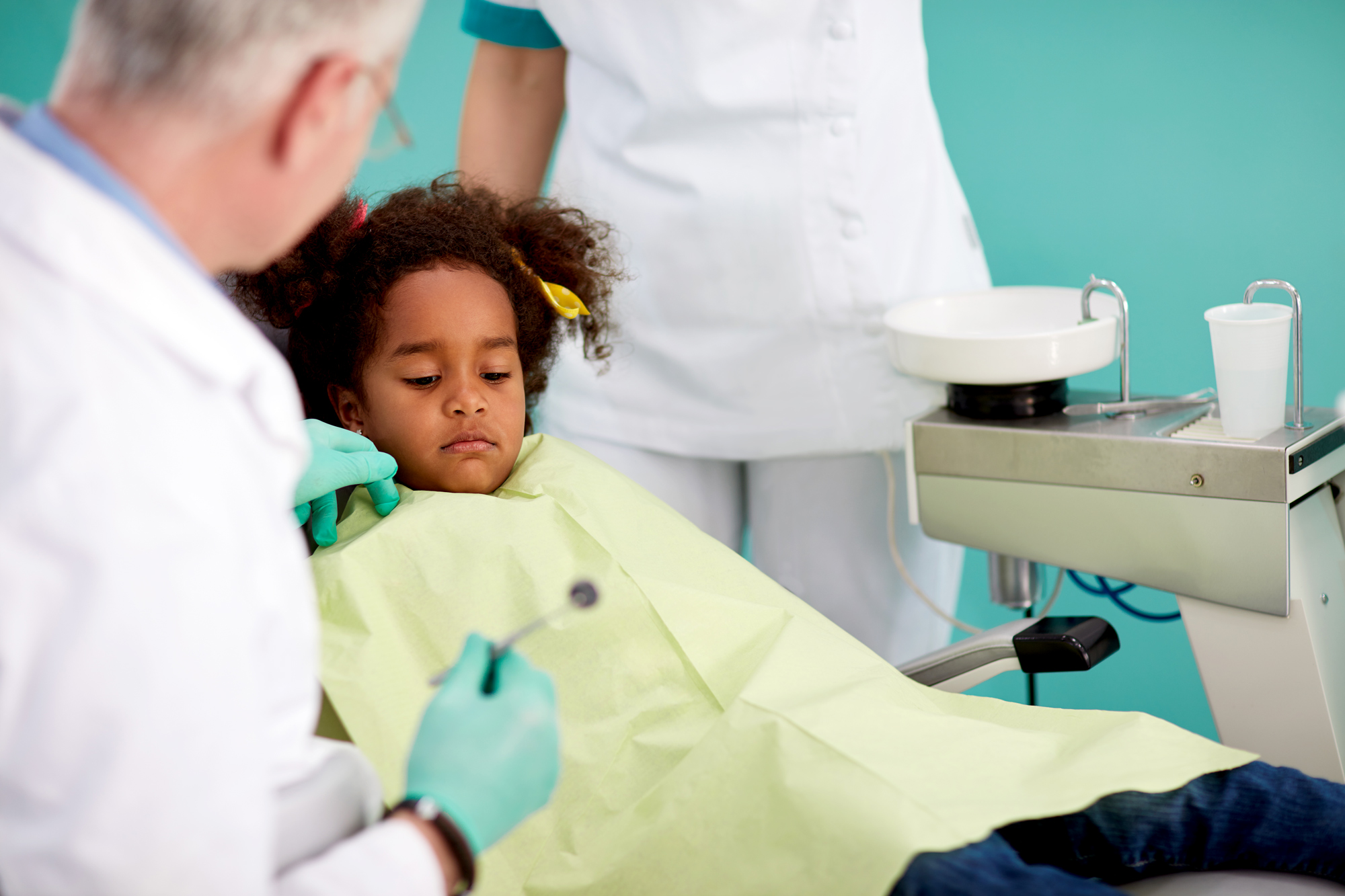 A little girl looks sad in the dentist's chair