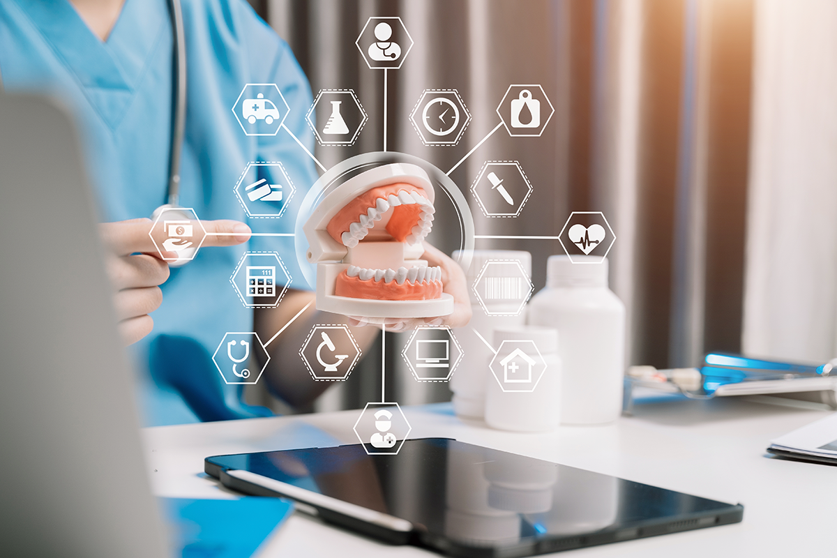A dentist holds up a model of a jaw with teeth, which is surrounded by projected graphics.