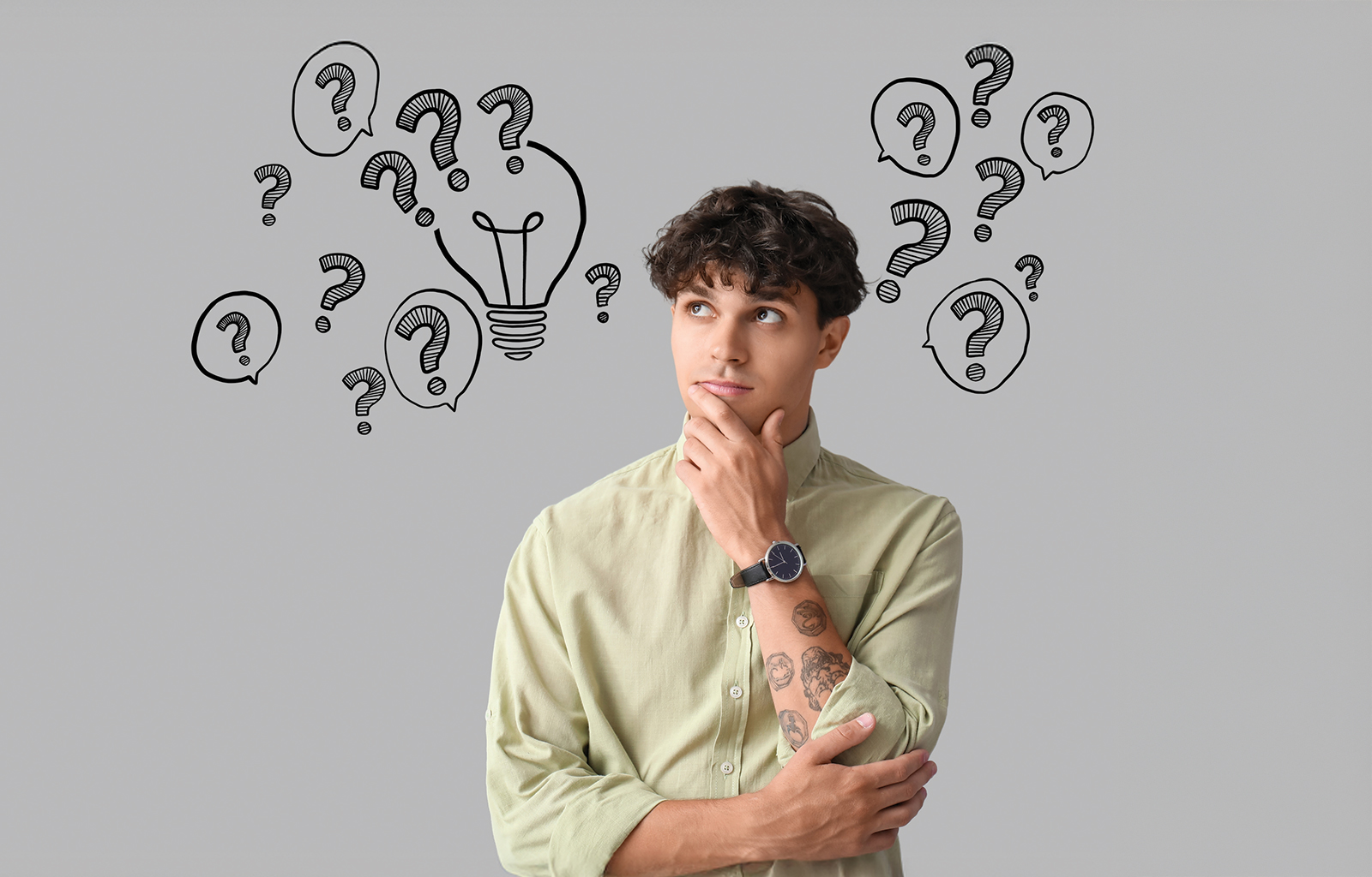 A man poses like he's thinking, a grey wall behind is filled with black line drawn question marks.