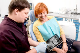 A dentist shows a patient her x-ray on a tablet device.