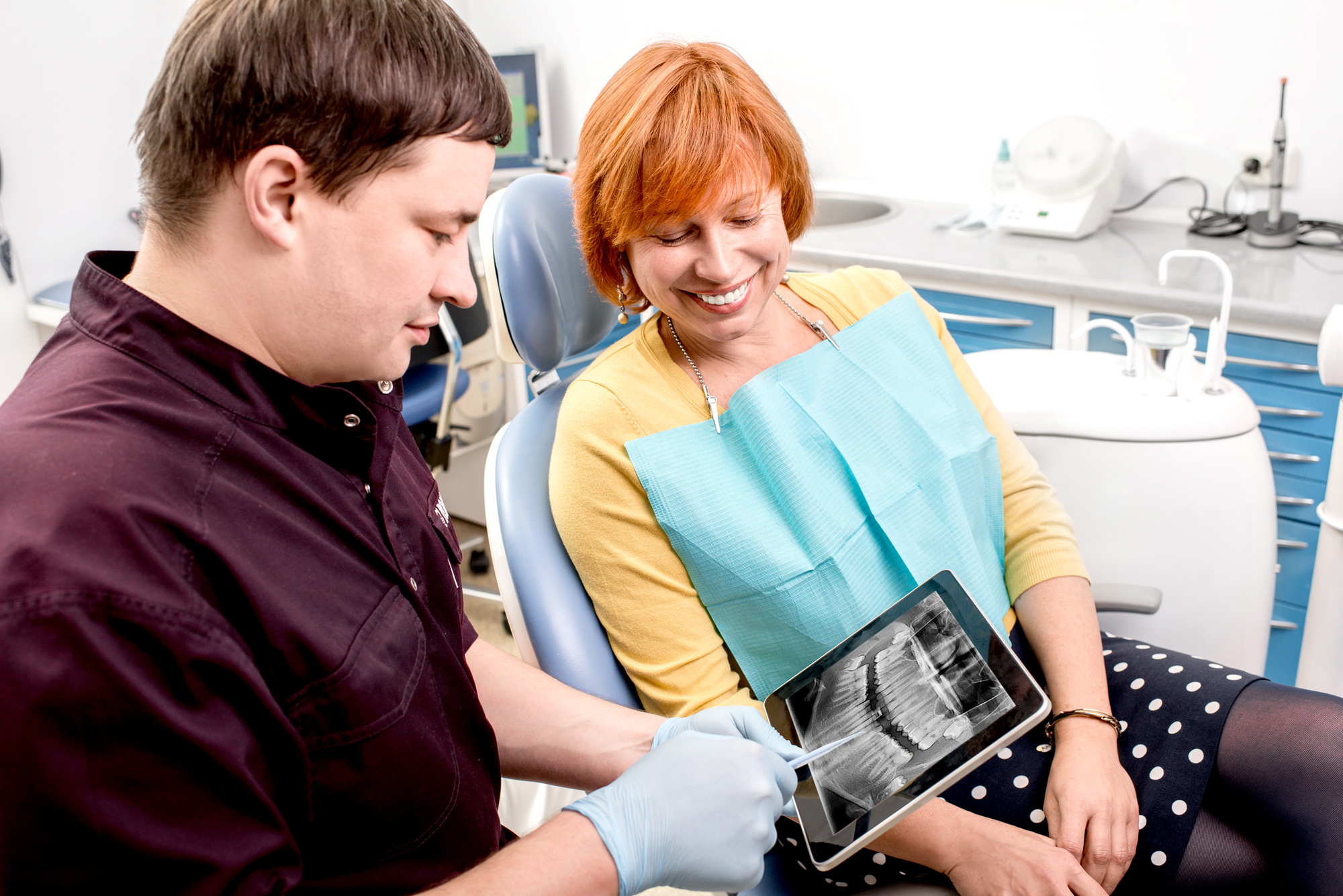 A dentist shows a patient her x-ray on a tablet device.