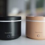 two round Sereclean pods with activation button on the front, one in black and one in tan.