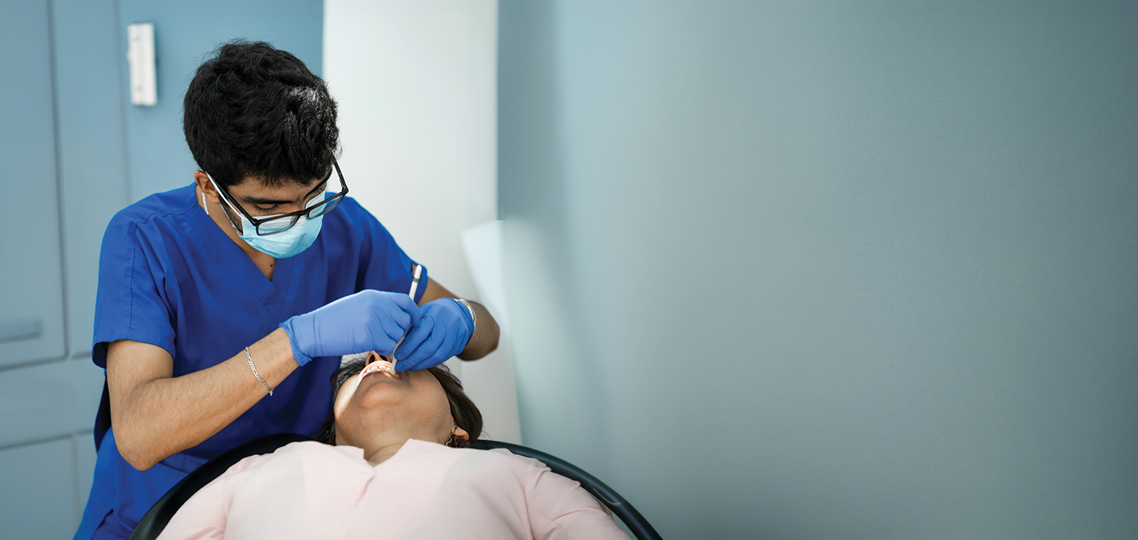 A dentist performs a treatment on his patient.
